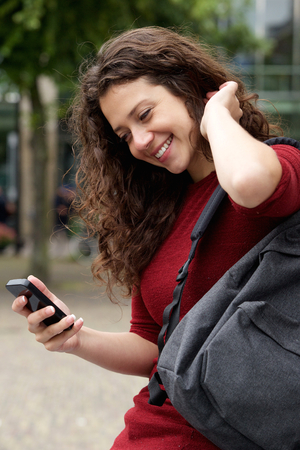 Close up portrait of happy young woman using mobile phone outdoorsの写真素材