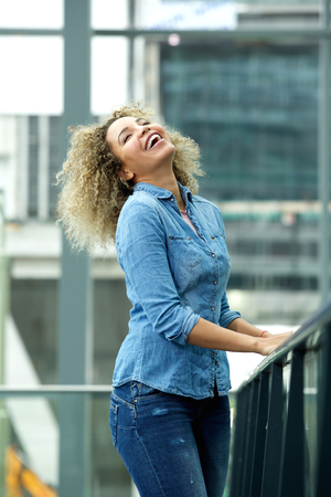 Portrait of laughing woman with head back and hands on railingの写真素材