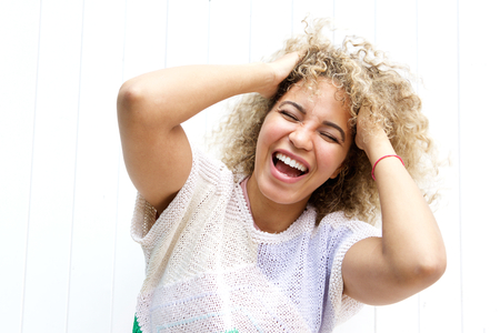 Close up portrait of young black woman laughing with hands in hairの写真素材