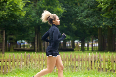 Side profile portrait of sporty young woman running outsideの写真素材