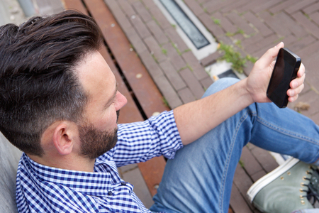 Close up portrait of mature man sitting outside and looking at his cell phoneの写真素材