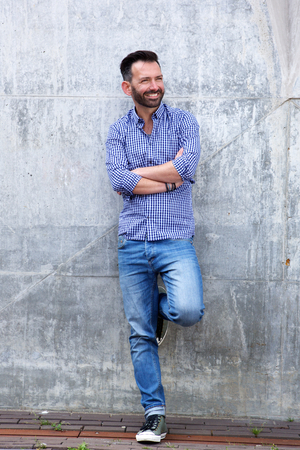 Full length portrait of confident mature man standing with arms crossed and looking awayの写真素材