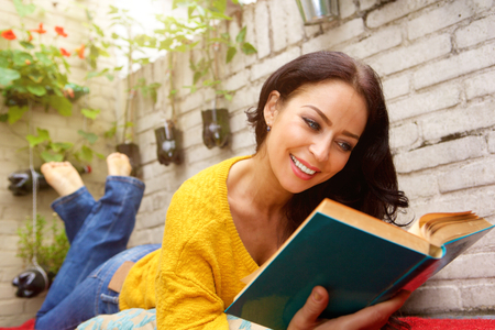 Close up portrait of smiling attractive woman reading bookの写真素材