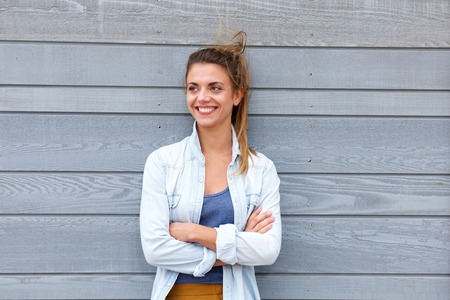 Portrait of happy woman standing with arms crossed and hair blowingの写真素材