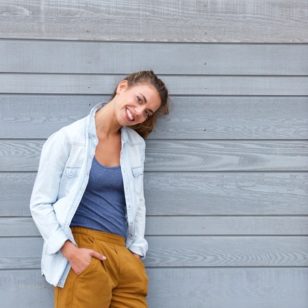 Portrait of smiling confident woman leaning against wall