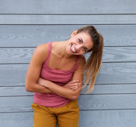 Portrait of smiling woman with hair in ponytail and arms crossed