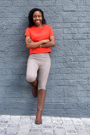 Full portrait of happy girl leaning against wall with crossed arms.の写真素材