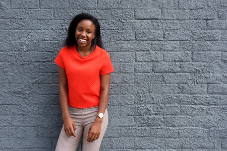 Portrait of young happy african woman laughing against gray wall.の写真素材