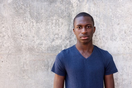 Close up portrait of young african man standing agaisnt gray wallの写真素材