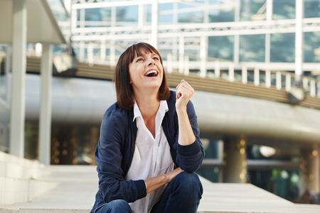 Portrait of laughing older woman sitting outside in cityの写真素材