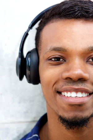 Close up half portrait of smiling man with headphones listening to music