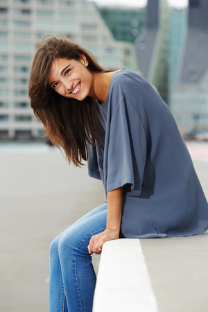 Portrait of beautiful young woman sitting outdoors and smilingの写真素材