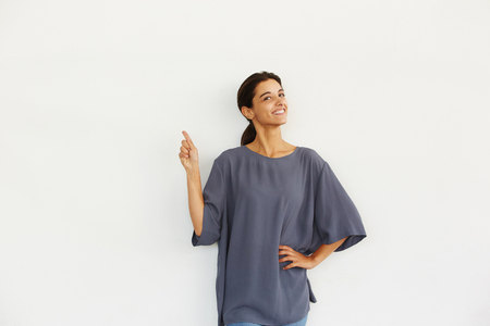 Portrait of cheerful young woman pointing at copy space over white backgroundの写真素材
