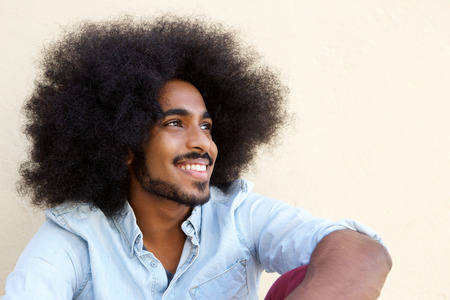 Close up portrait of happy afro man sitting and looking awayの写真素材