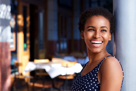 Side portrait of smiling young black woman standing outsideの写真素材