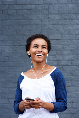 Portrait of young smiling woman listening to music with earphones and cell phoneの写真素材