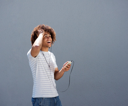 Portrait of young man smiling with earphones and mobile phoneの写真素材