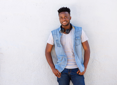 Portrait of smiling man with headphones standing against white wallの写真素材