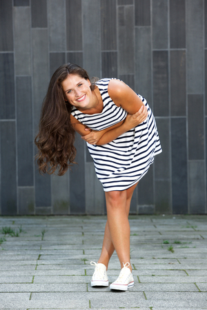 Full length portrait of young happy woman bending with crossed armsの写真素材
