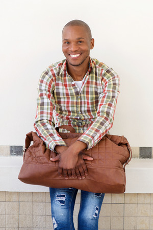 Portrait of happy male traveler sitting with bagの写真素材