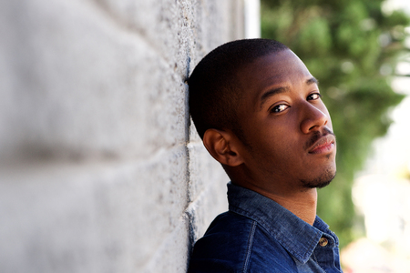 Side portrait of young african man leaning against wallの写真素材