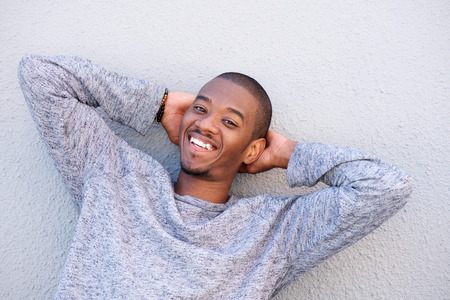 Portrait of happy young black guy smiling with hands behind headの写真素材