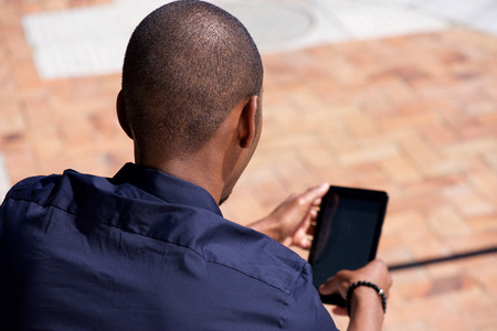 Back of african american man using digital tablet outdoorsの写真素材