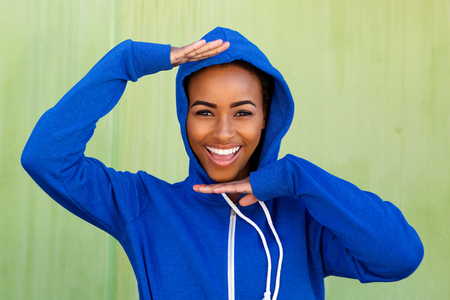 Portrait of cool young black woman smiling with hands raised