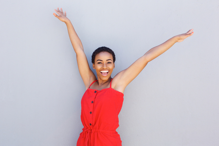 Portrait of beautiful young black woman smiling with arms raisedの写真素材