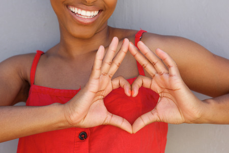 Close up portrait of young woman smiling with heart shape hand signの写真素材