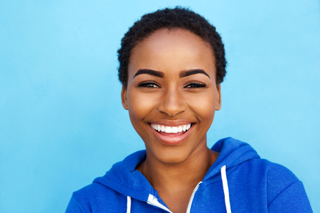 Close up portrait of smiling young black woman against blue backgroundの写真素材