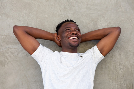 Close up portrait of young african american man smiling with hands behind headの写真素材