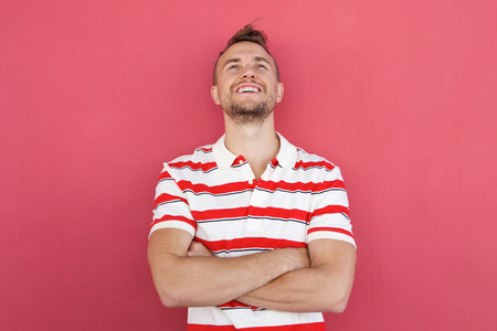 Portrait of smiling young man standing against red wall looking upの写真素材