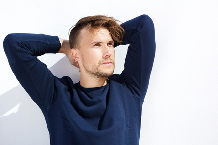 Portrait of cool fashion guy looking away with hands behind head