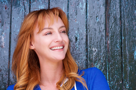 Close up portrait of happy woman standing by wall laughingの写真素材