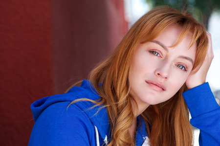 Close up portrait of young woman in contemplation leaning head on handの写真素材