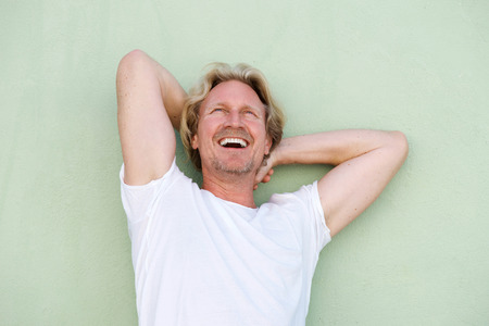 Portrait of middle aged guy laughing with hands behind headの写真素材