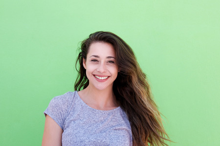 Front portrait of smiling young woman standing against green background