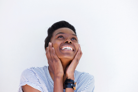 Close up portrait of young woman laughing with hands on face against white backgroundの写真素材