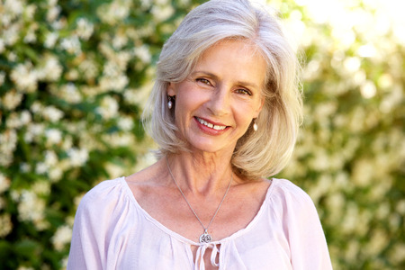 Close up portrait of happy older woman standing in gardenの写真素材