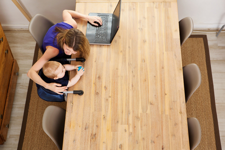 Top view portrait of mother working on laptop and playing with her sonの写真素材