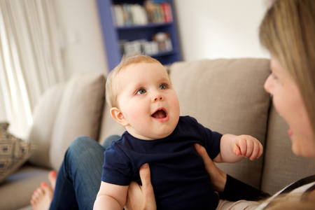 Close up portrait of cute little baby boy with his mother on sofa at home