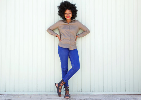 Full length portrait of happy woman standing by white wall with confidenceの写真素材
