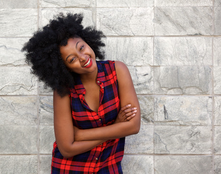 Portrait of young african woman smiling by stone wallの写真素材
