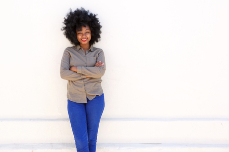 Portrait of smiling woman standing with arms crossed against white backgroundの写真素材