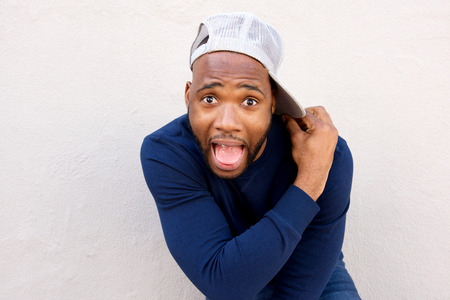 Portrait of crazy young african man with cap standing by wallの写真素材