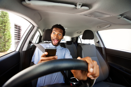 Close up portrait of distracted man driving in car holding phone