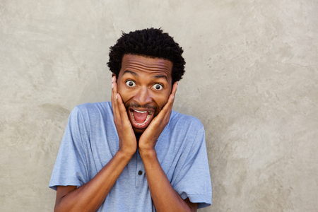 Close up portrait of handsome man with hands to face in surprised expressionの写真素材