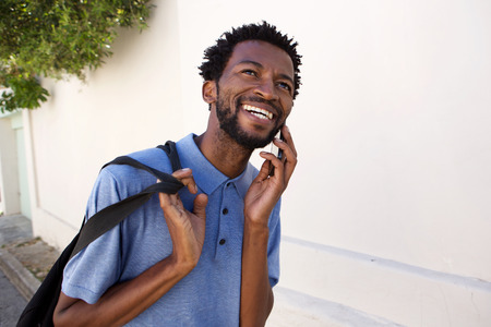Portrait of smiling black man walking outside on telephone call