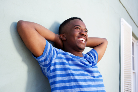 Portrait of happy young african man smiling with hands behind headの写真素材